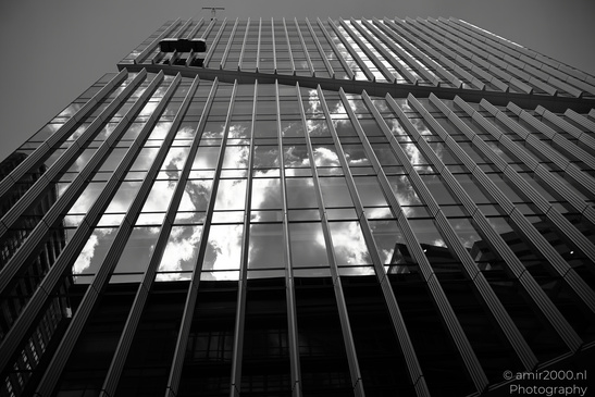 A towering skyscraper reflects the sky and clouds in its glass facade. - image from year 2026 #003