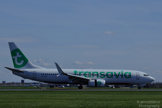A Transavia aircraft is taxiing on the runway under a clear sky, surrounded by grassy areas and - image from year 2026 #003