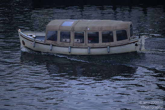 Boat_With_12_Pass_On_Side_Cruising_At_Dusk_In_Canal_Amsterdam_Netherlands_Cityscape_Photography_Canon_EOS_R5_Mark_II_2026_001.JPG