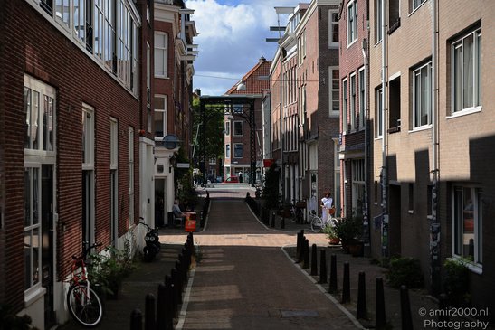 A narrow street lined with brick buildings on both sides, featuring bicycles parked along the - image from year 2026 #004