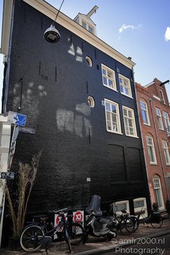 A dark blue brick building with white framed windows, a small attic window, and a sign - image from year 2026 #009