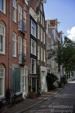 A narrow street lined with traditional brick buildings featuring white framed windows and - image from year 2026 #010