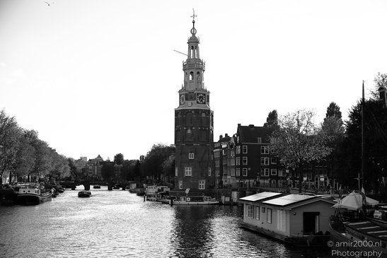 A canal with boats and a clock tower, indicating a reflection in the water in Amsterdam, - image from year 2026 #002