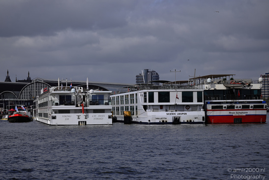 Three river cruise ships docked side by side on a body of water with buildings and structures in - image from year 2026 #001