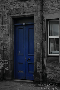 A dark stone building with a blue double door marked "27" and a window to its right in Scotland - image from year 2026 #004
