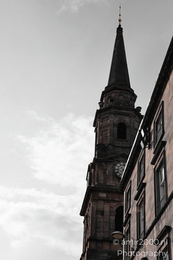 A tall church spire with a clock face and a weather vane on top, set against a cloudy sky next - image from year 2026 #011