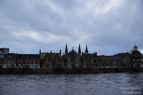 A Scottish cityscape with a church and buildings by the water under an overcast sky. - image from year 2026 #016