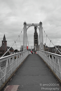 A pedestrian bridge in a Scottish city with historic buildings and a clock tower. - image from year 2026 #029