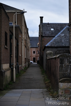 A narrow alleyway in a Scottish city with old buildings and a stone wall. - image from year 2026 #031