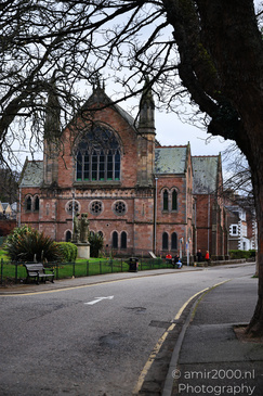 A historic church with a tall spire and arched windows stand in the middle of a tree lined - image from year 2026 #041
