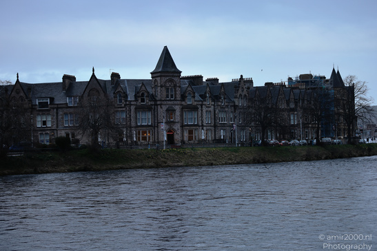 A Scottish cityscape with historic buildings by a river at dusk. - image from year 2026 #042