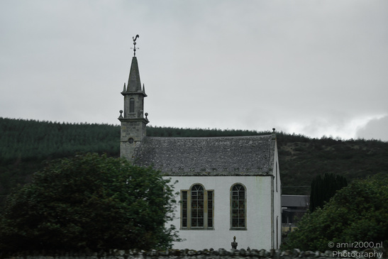 Scottish City Inverness a quaint church with a tall steeple and a weathervane stands amidst lush - image from year 2026 #047