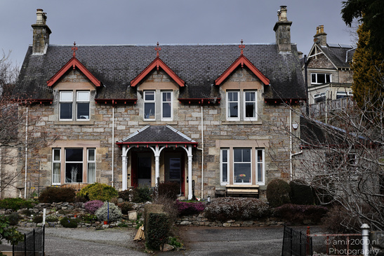 Town Pitlochry a quaint stone house with red trim and a welcoming porch. - image from year 2026 #004