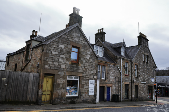Town Pitlochry a quaint stone building with a yellow door and a sign advertising books. - image from year 2026 #006