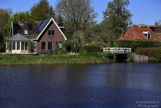 Village with a pond and traditional houses under clear blue skies. - image from year 2026 #003