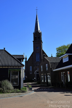 A quaint village street with a church under a clear blue sky. - image from year 2026 #006