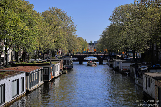 Canal with houseboats on either side and a bridge in the distance. - image from year 2026 #001