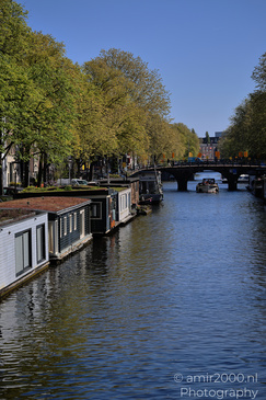 Canal with houseboats lining the water and a bridge in the distance. - image from year 2026 #002