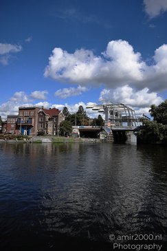 Willemsbrug Haarlemmerplein canal with a bridge and historic buildings under a partly cloudy sky - image from year 2026 #003