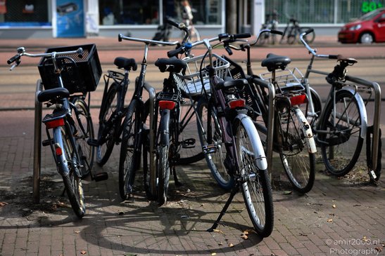 Bicycles parked in a bike rack on a sidewalk in Amsterdam, Netherlands. - image from year 2026 #001