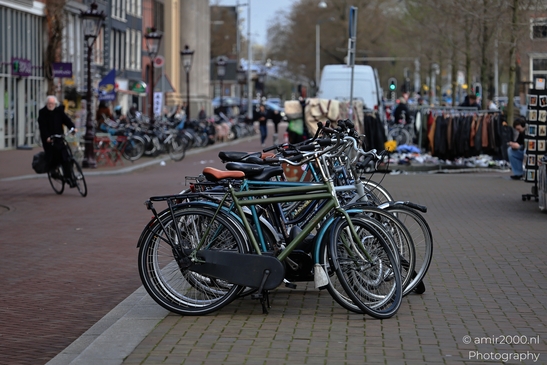 Clear view of bicycles lined up along a brick-paved sidewalk in Amsterdam, Netherlands. - image from year 2026 #001