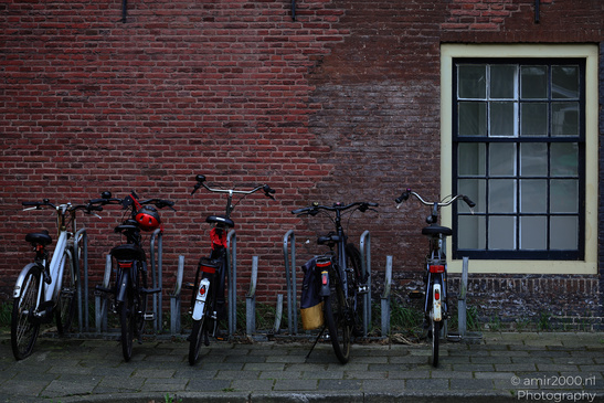 Bicycles appear and parked against a brick wall in Amsterdam, Netherlands. - image from year 2026 #002