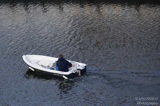 A man operating a motorboat with a cooler on a canal in Amsterdam. image from year 2026 #1