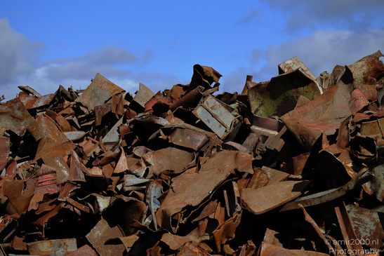A pile of rusted metal debris under blue sky with scattered clouds. - image from year 2026 #004