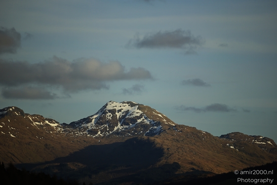 A mountain range with snow capped peaks under a partly cloudy sky in Scotland United Kingdom. - image from year 2026 #009