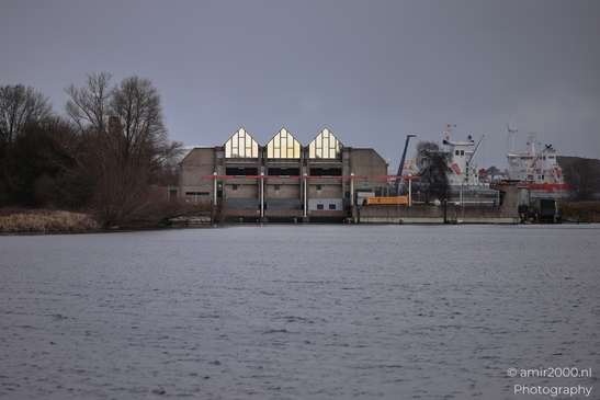 Winter scene of industrial buildings by a canal with ships docked nearby. image from year 2026 #1