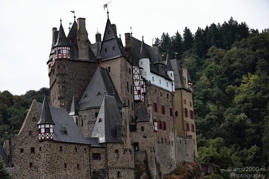 A medieval castle with towers and turrets, surrounded by lush greenery and trees in Rhineland - image from year 2026 #004