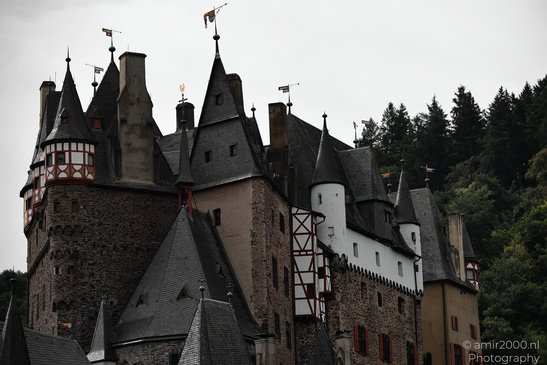 A medieval castle with multiple towers, turrets, and steeply pitched roofs, surrounded by a - image from year 2026 #005