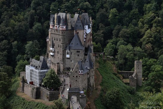 A medieval castle perched on a rocky hill, surrounded by lush greenery and a winding path - image from year 2026 #011