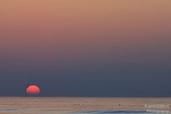 A sunset over the North Sea, with a red sun setting in the distance. - image from year 2026 #020