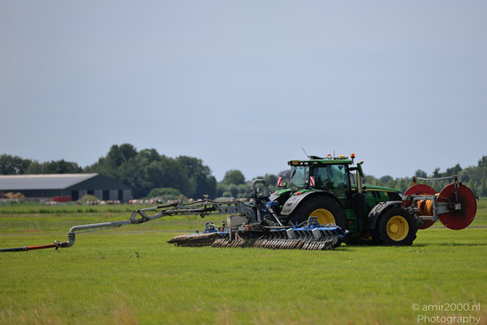 A green tractor works across a grassy field at De Hoge Dijk under a pale blue sky. image from year 2026 #5
