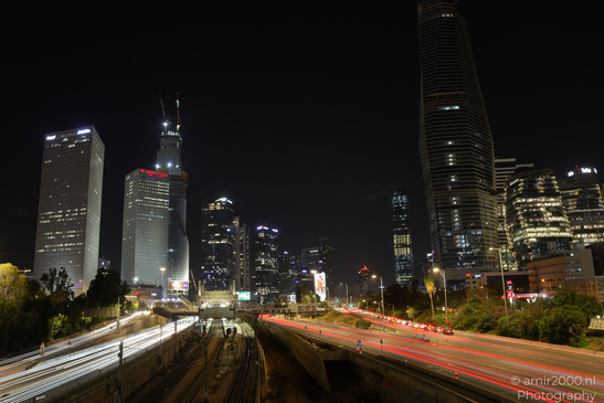 A nighttime cityscape with several prominent skyscrapers illuminated against a dark sky in Tel - image from year 2026 #005