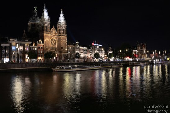 A canal with boats and buildings on either side, illuminated at night, creating reflections on - image from year 2026 #001