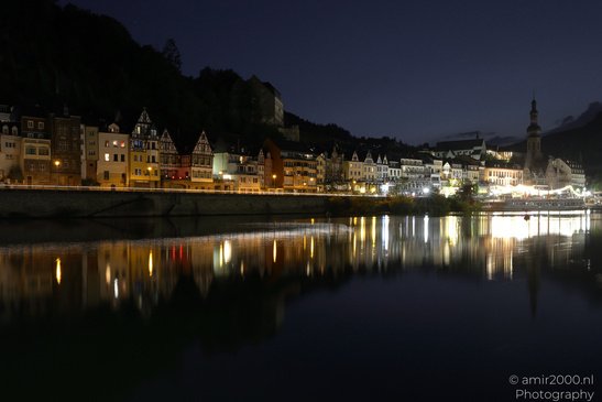 A serene night scene of a riverside town, with illuminated buildings reflecting on the calm - image from year 2026 #007