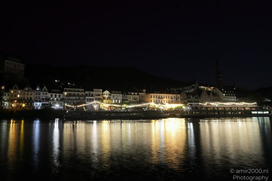 A serene night scene of a riverside town illuminated by lights, with buildings and a church - image from year 2026 #009