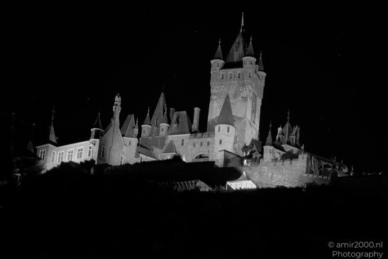 A large, multi towered castle at night, with a dark sky and some faintly visible structures in - image from year 2026 #011