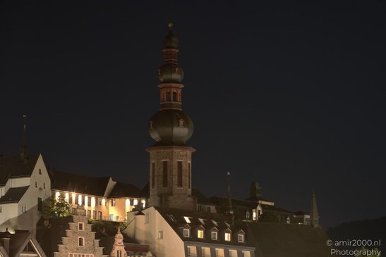 A tall tower with a domed roof in the foreground, surrounded by buildings with illuminated - image from year 2026 #013