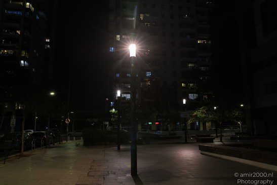 A lone street lamp illuminates a quiet urban plaza at night. - image from year 2026 #004