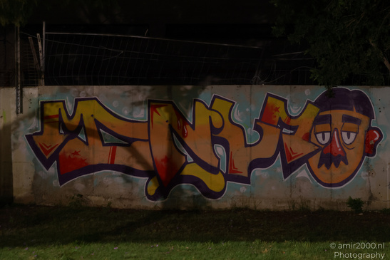 A colorful graffiti mural of a cartoonish face on an urban wall at night. - image from year 2026 #005